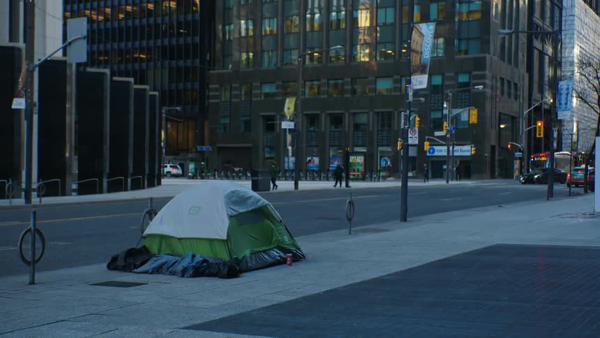 A tent erected on the sidewalk of a metropolis during the day