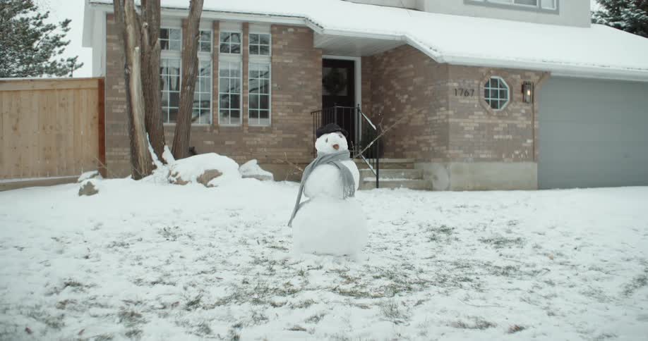 A snowman in front of a house
