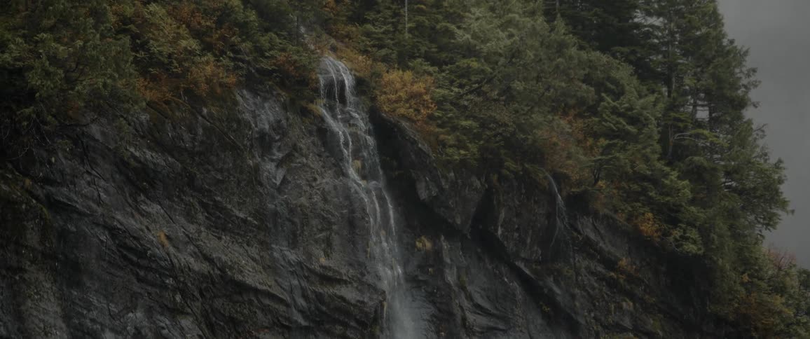 Waterfall flowing down the rock surface of a mountain on an overcast day