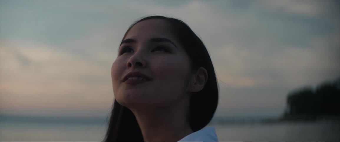 A woman smiles as she turns and takes in the view at the beach