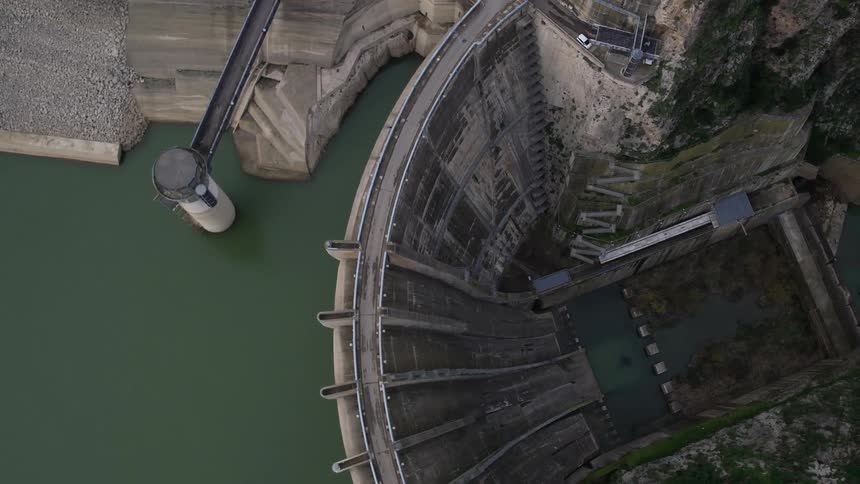 A tall dam complex is seen from above