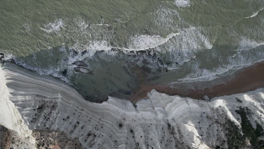 Waves crash on the beach of a mountain side coastline