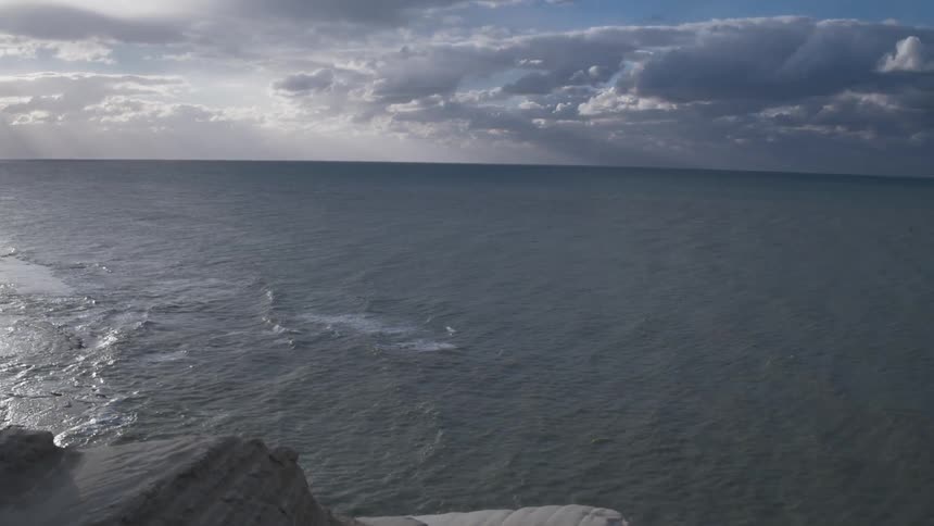 The ocean just past a mountainous coast line on an overcast day