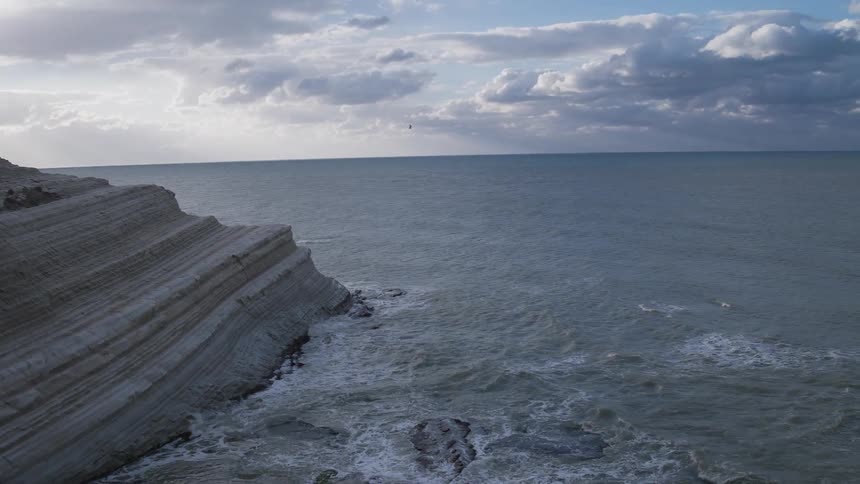 Water brushes against the side of a worn cliff