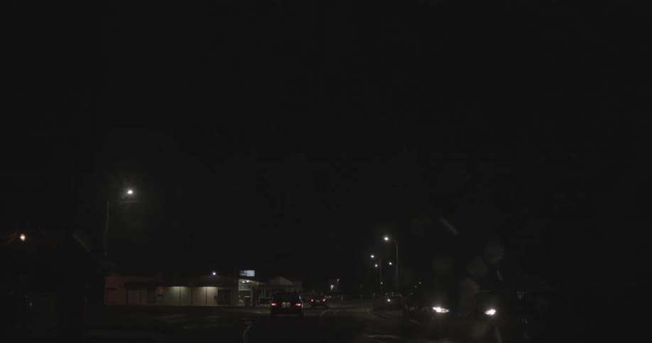 Cars driving on a small town at night under a thunderstorm