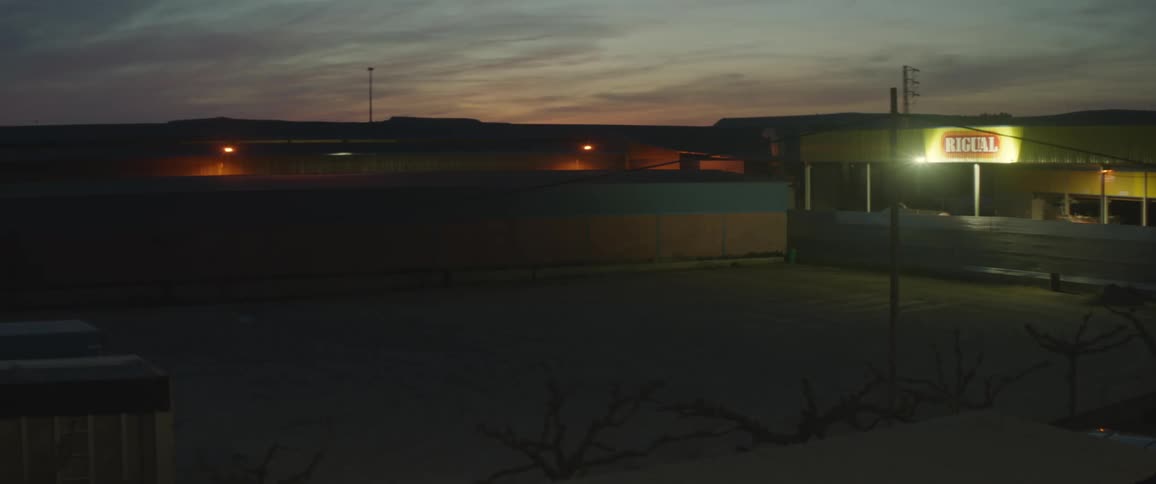 Light comes on to illuminate shadowy part of empty parking lot furthest from light shining around store sign at night