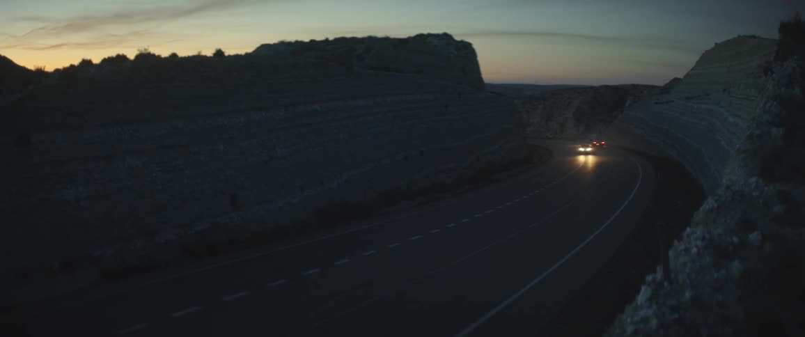 Cars traveling on a remote road at dusk