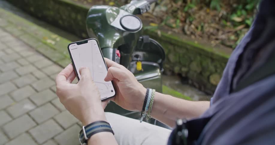 A man uses a mapping app on his phone while sitting on his motorcycle