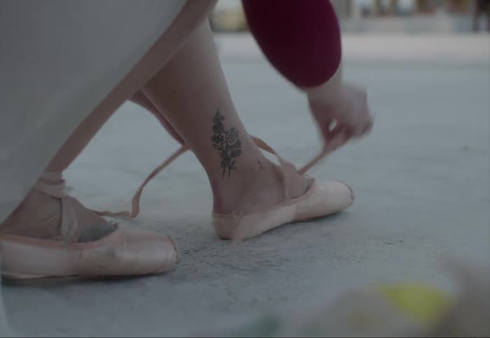 Ballerina sits on step putting on toe shoes