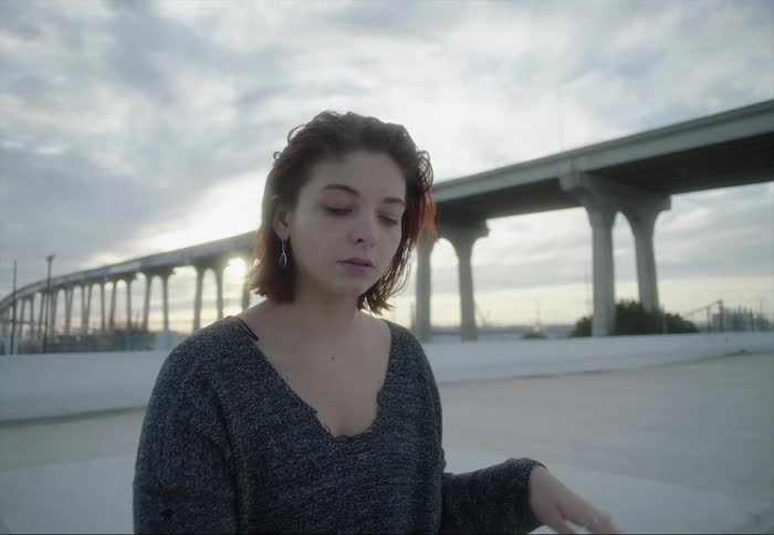A young woman looks at her smartphone making hand gestures as she is singing