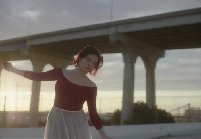 A ballet dancer dances on the beach near a bridge