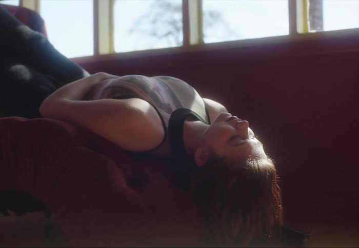 Young woman reclined upside down on a couch in the living room stretching