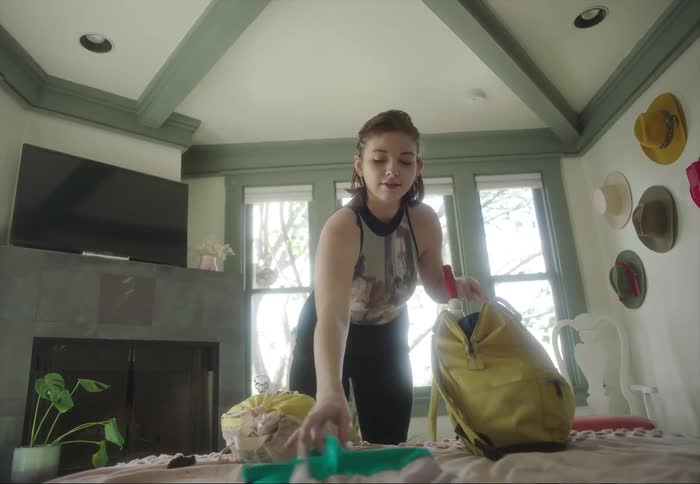 Young woman packing clothes on bags over the bedroom at home