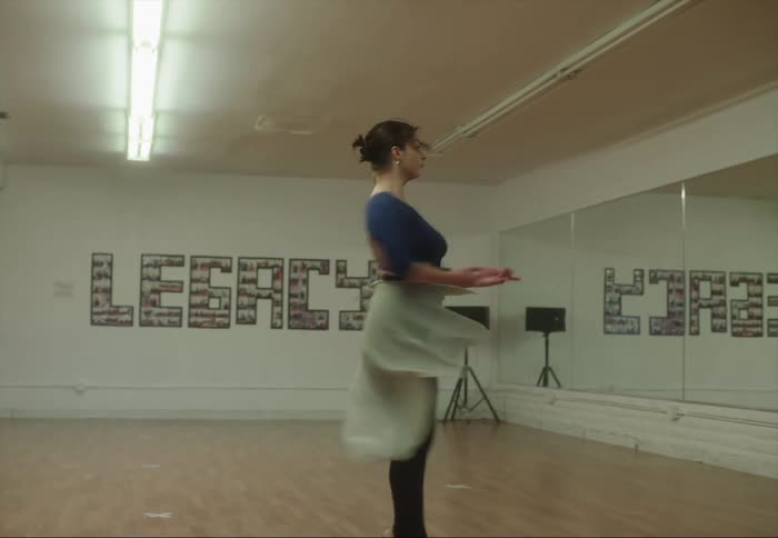 A woman is twirling around as she dances across the room