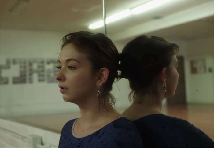 A dancer is resting against the mirror