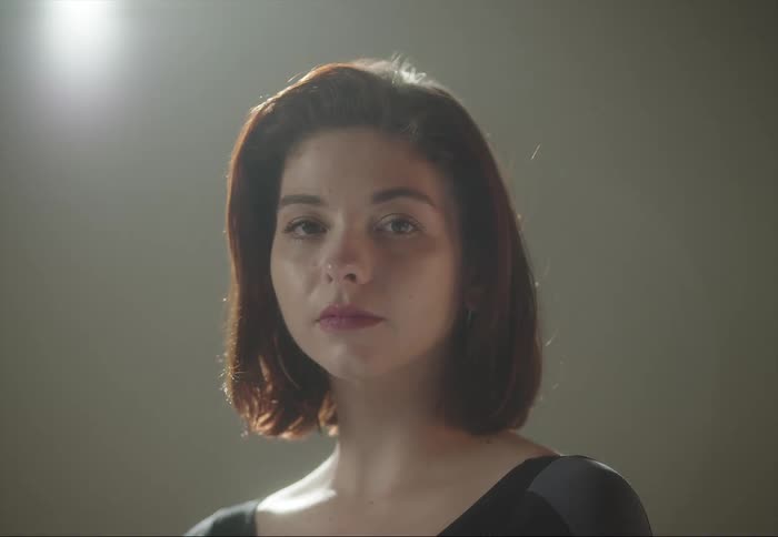 Woman looks forward backlit from above by a bright electric light