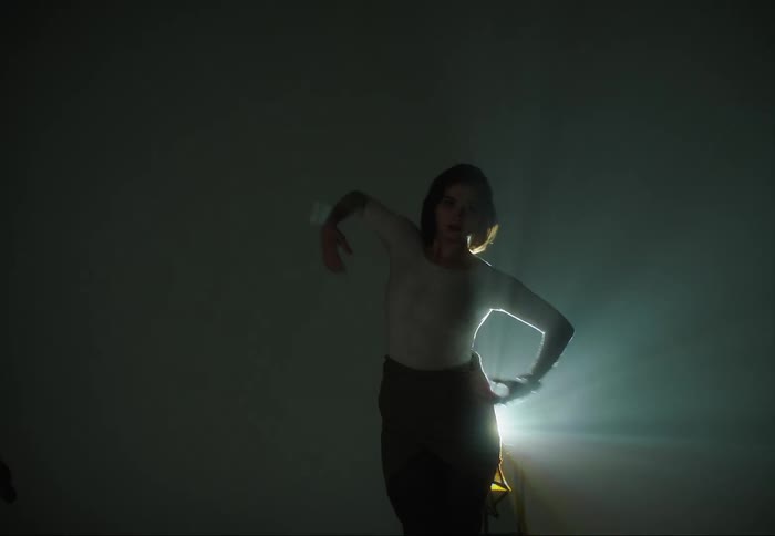 Silhouette of a young woman dancing in front of shifting colorful lights