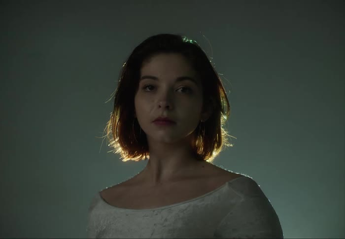Young woman standing in front of shifting colorful lights looking at the camera