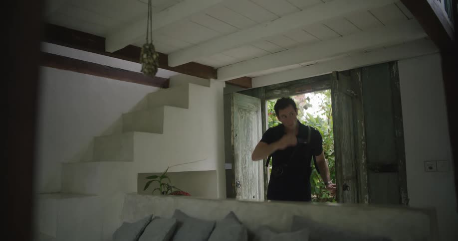 A man takes off his sunglasses after walking into a home