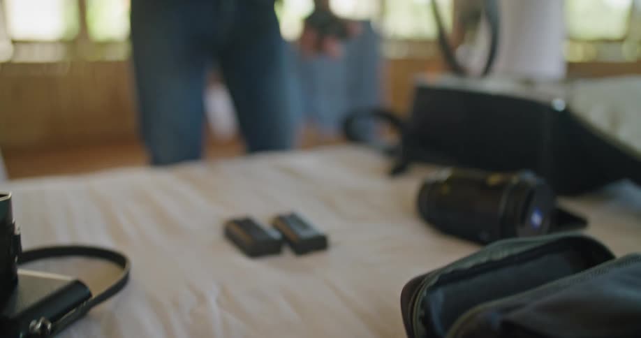 A man is standing over a table packing his camera and photography equipment into a case