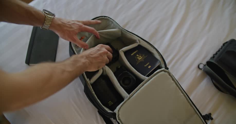 A man puts his camera and passport into a backpack and takes it with him