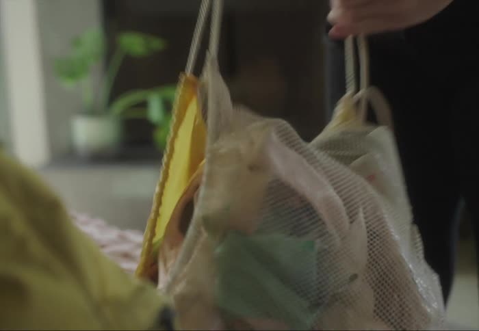 A person places a pair of pointe shoes in a cinch bag and pulls the drawstring to close the bag