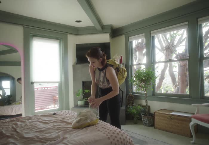 Young woman picks up her bags from the bed in the bedroom before going out
