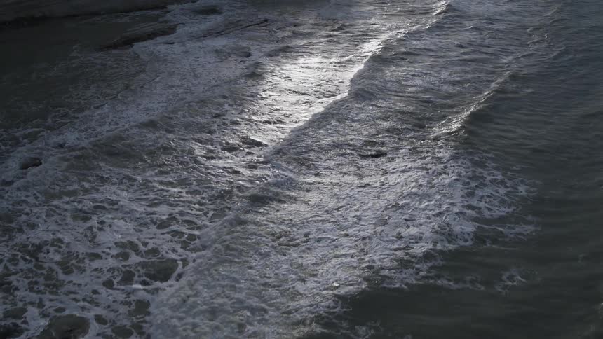 Waves washing against a coastline during sunset