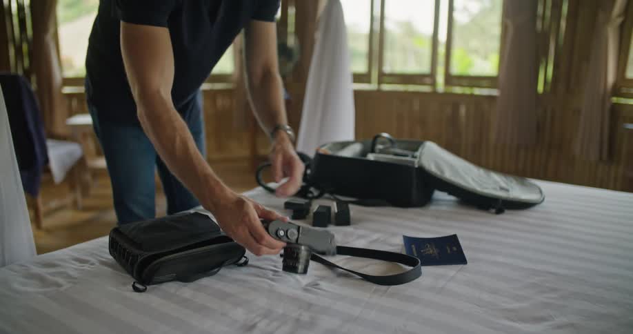Photographer checks his cameras before packing them on a backpack on a hotel bedroom