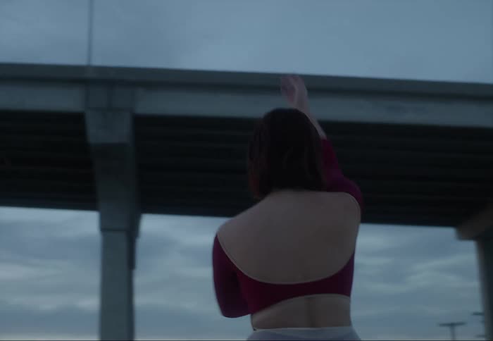 A ballerina dances on the rooftop of a building in a city in the evening