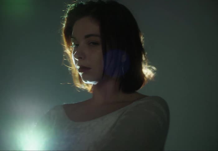 Young woman dances waving her arms around in front of shifting colorful lights