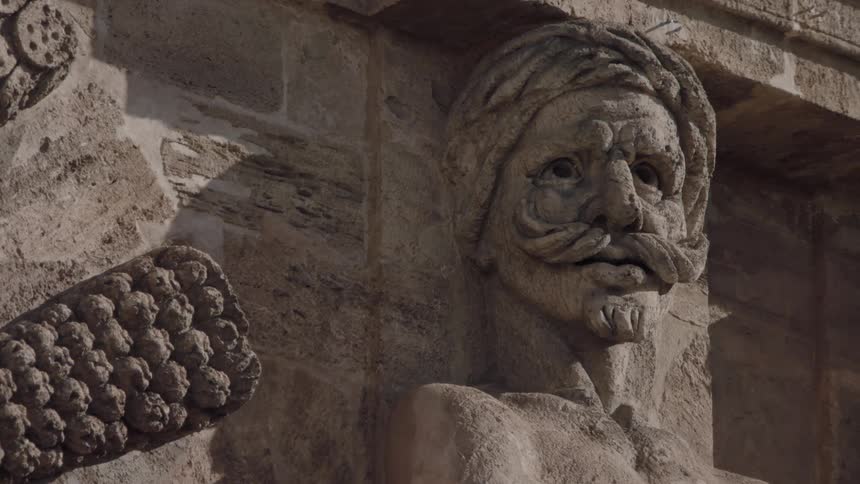 The side of a stone wall has men's faces carved into it
