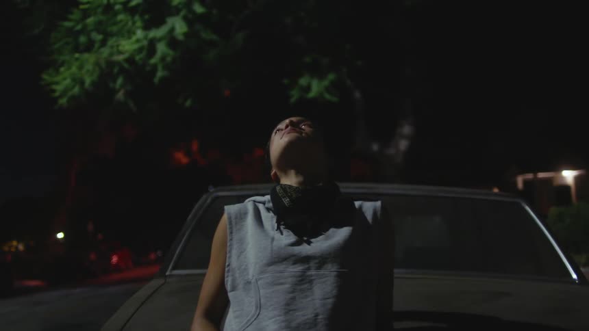 A woman leans against a car taking a break from working out and a deep breath