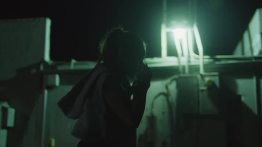 A woman shadow boxes outdoors at night