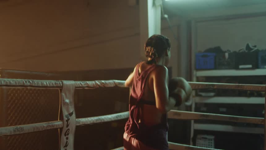 Young female boxer shadow boxing in the corner of a ring