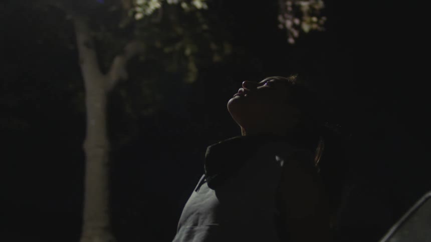A woman is stretching outside at night