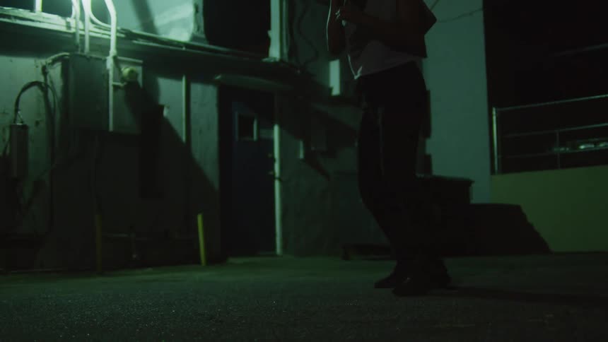 Woman shadowboxes in alley at night