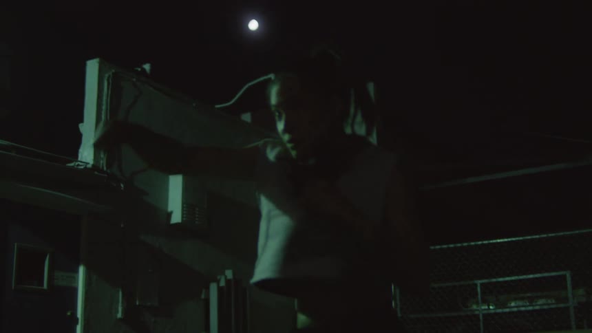 Young female boxer shadow boxing in an alleyway at night