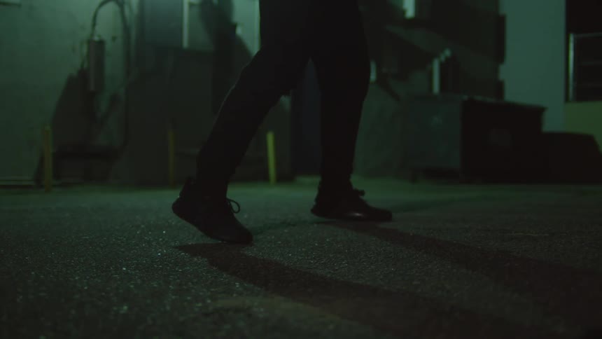 A woman is shadowboxing at night