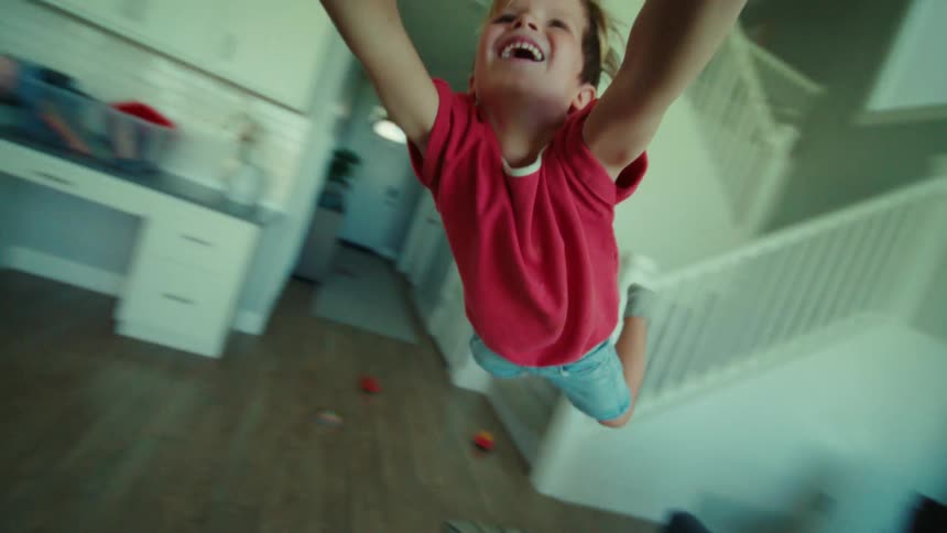 An adult is holding a little boys hands and swinging him off the ground in a circle