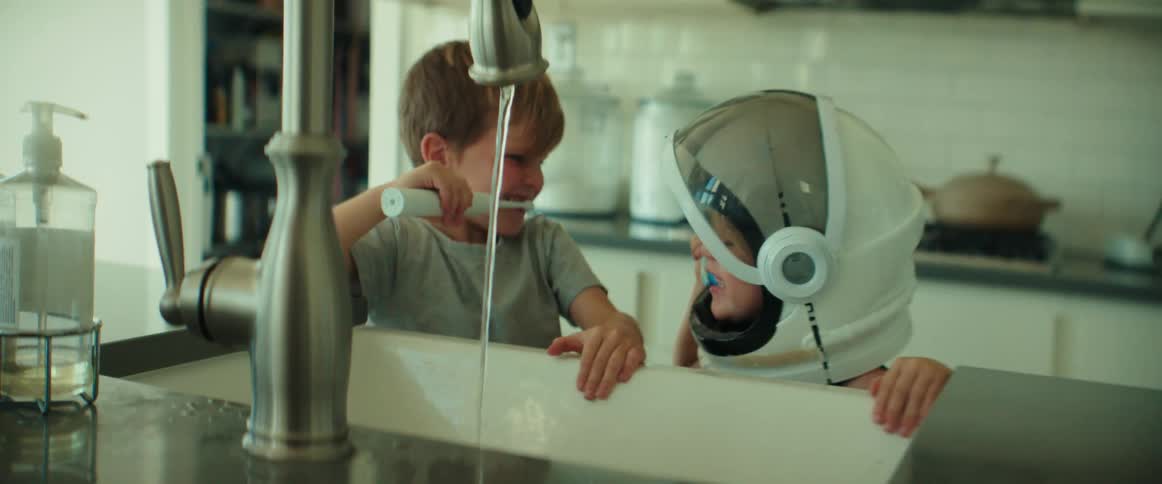 Young brothers playfully brushing their teeth on the kitchen sink at home