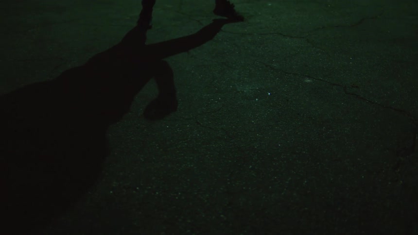 Woman shadow boxing on an alley at night