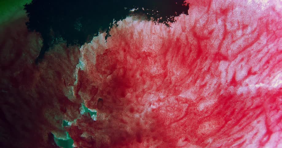 Black liquid ink flowing over a background of red streaks