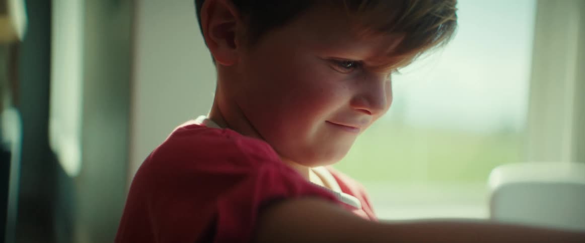 Boy smiles while playing with a toy car inside the home
