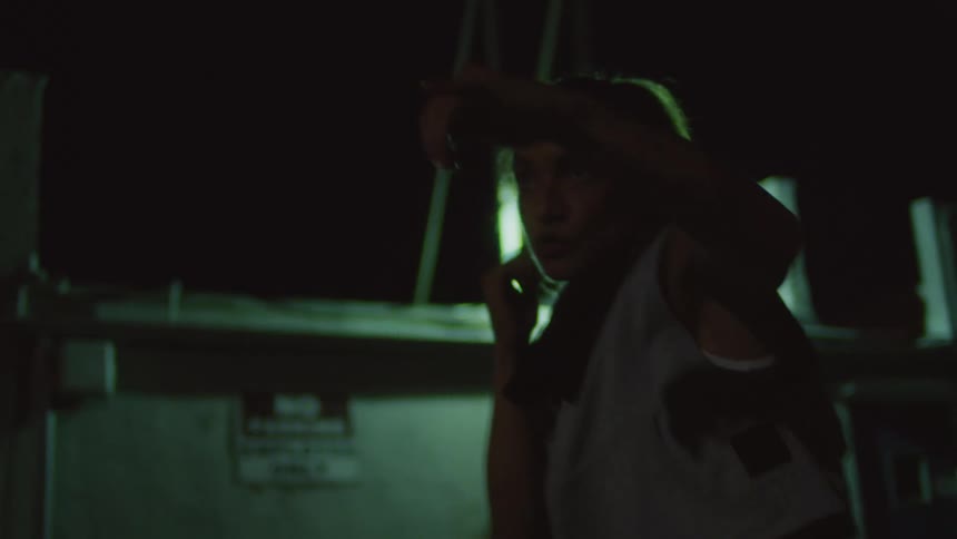 A woman shadow boxes outdoors at night