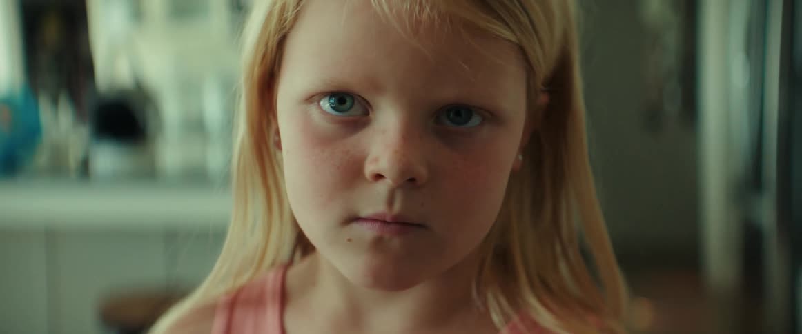 Blonde girl stands staring with a set jaw and a frown