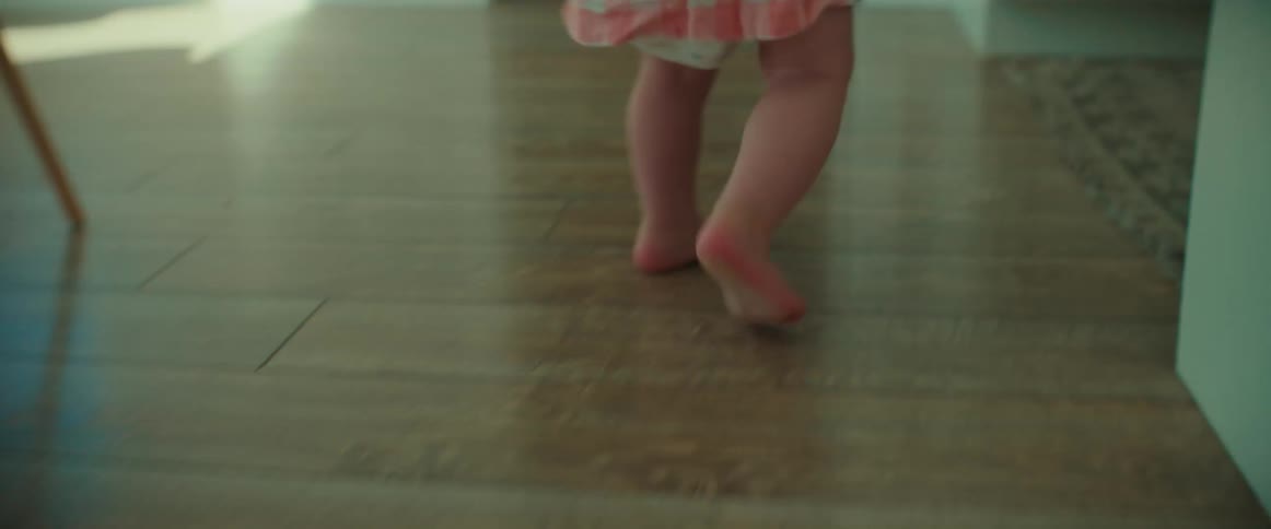 Barefoot toddler walking on the hardwood floor of the living room at home