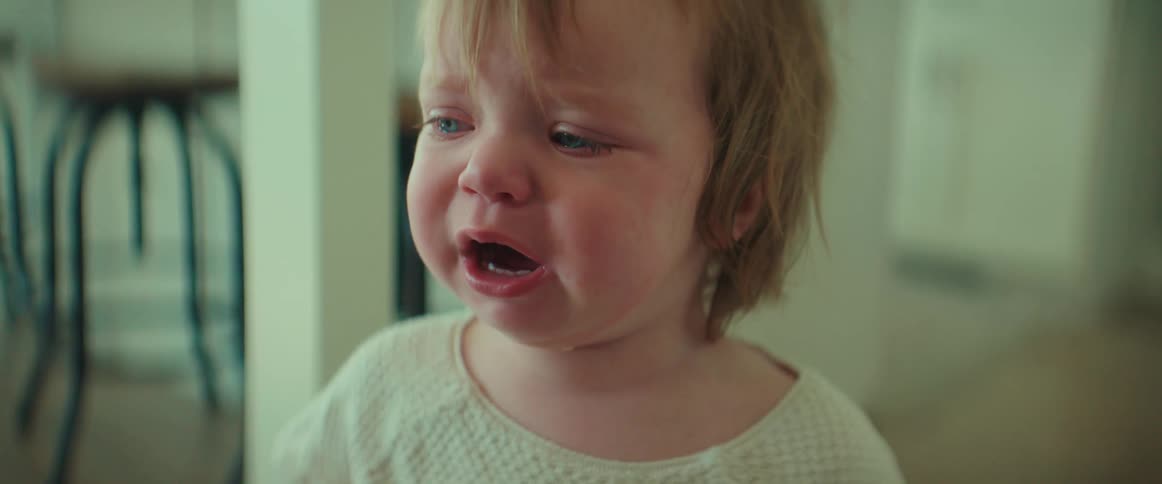 A little girl red faced and crying with her mouth open pauses then starts again