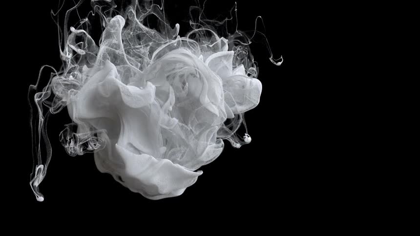 White paint flows downward against a black background and grows filmy as it spreads