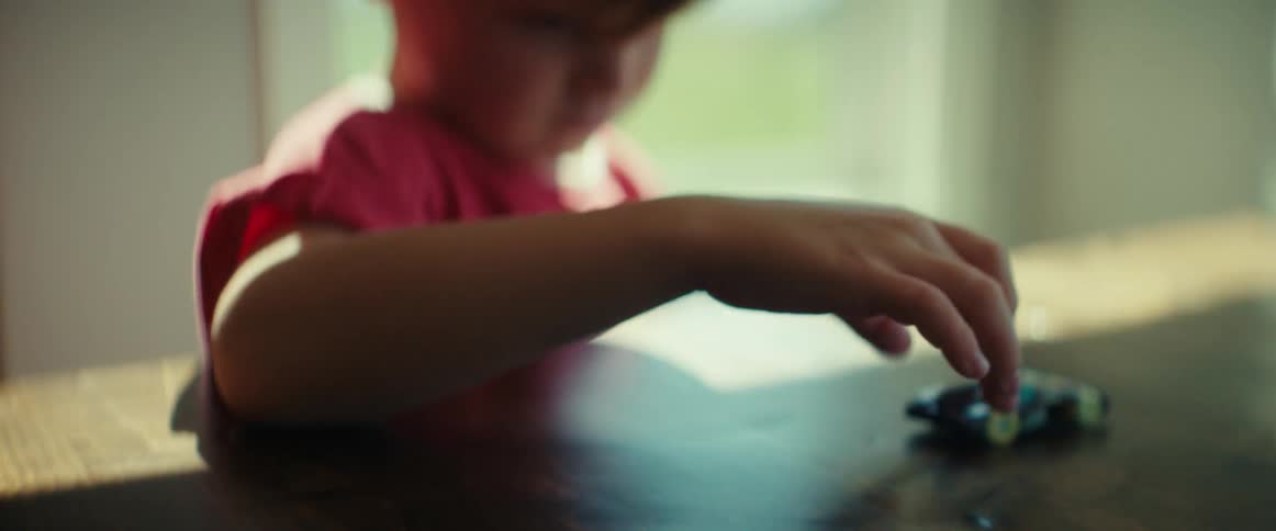 Young boy playing with a toy car on the living room table